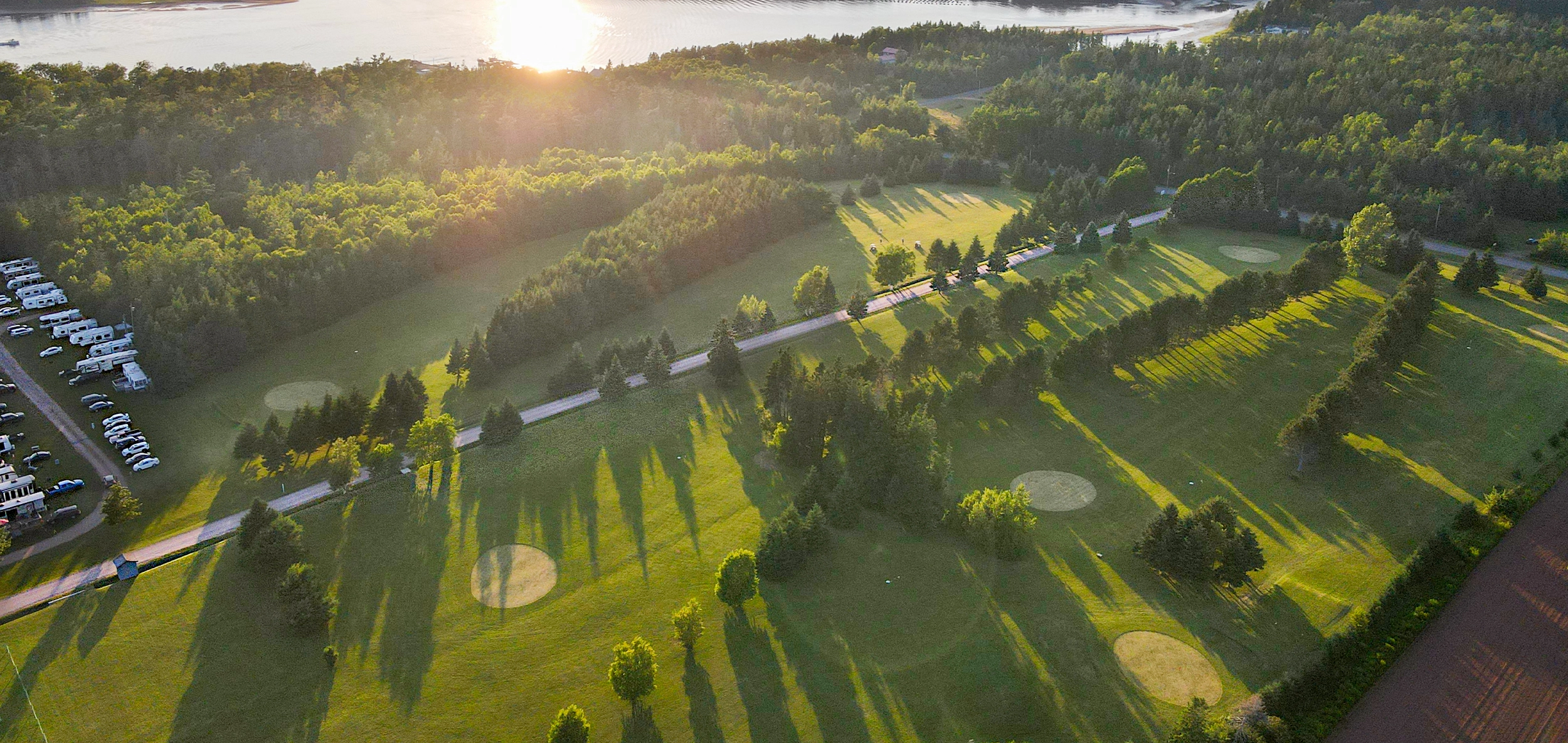 Aerial view of the Seal Cove golf course fairways at sunset beside the bay