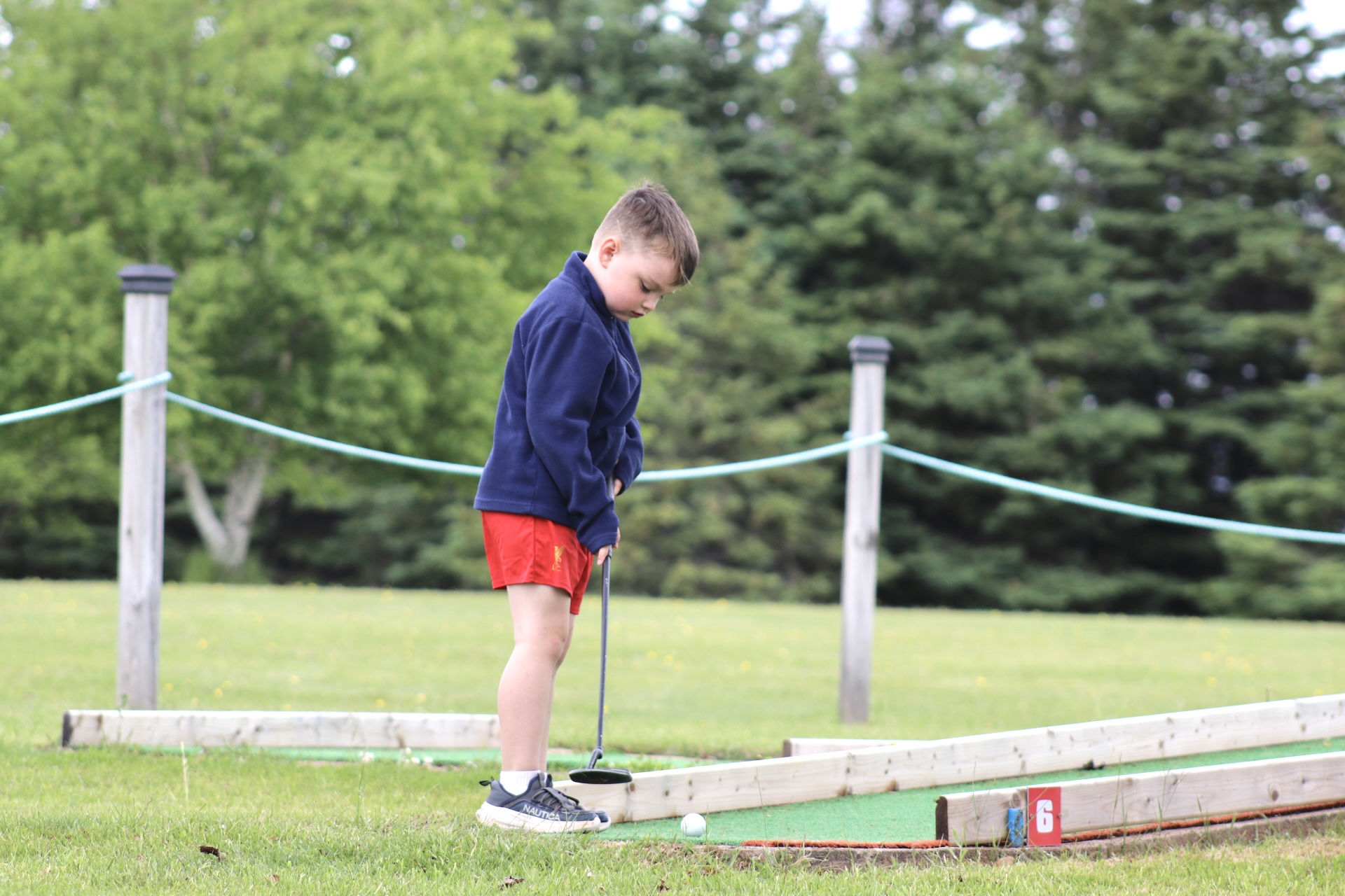 A young camper putting on the mini-golf course at Seal Cove